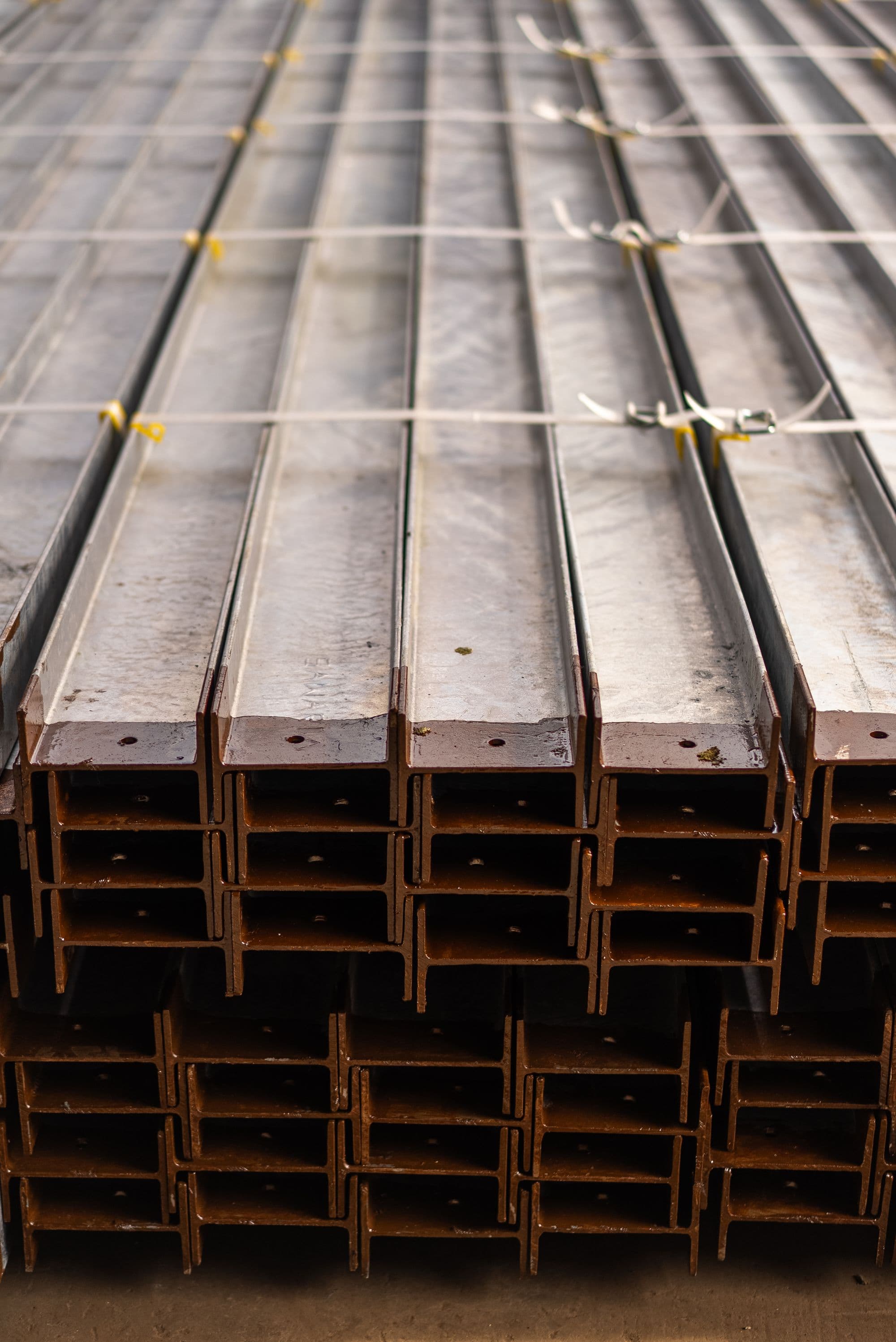 Rows of structural steel members staged for processing